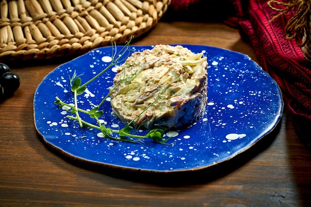 Salada Olivier com picles de frango e maionese em um prato sobre fundo de madeira