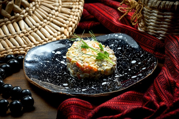 Salada Olivier com picles de frango e maionese em um prato sobre fundo de madeira