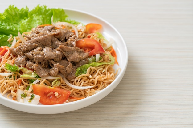 Salada picante de macarrão instantâneo com carne de porco no prato branco