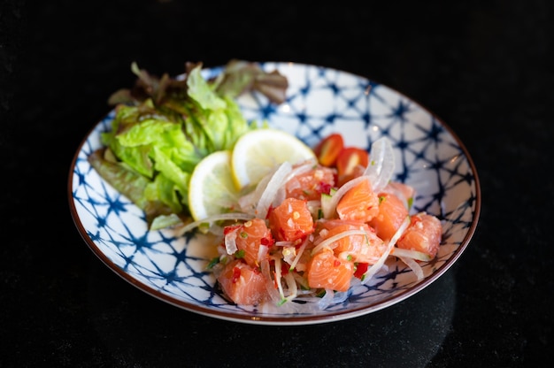 Salada picante de sashimi de salmão com vegetais em prato de cerâmica em restaurante japonês