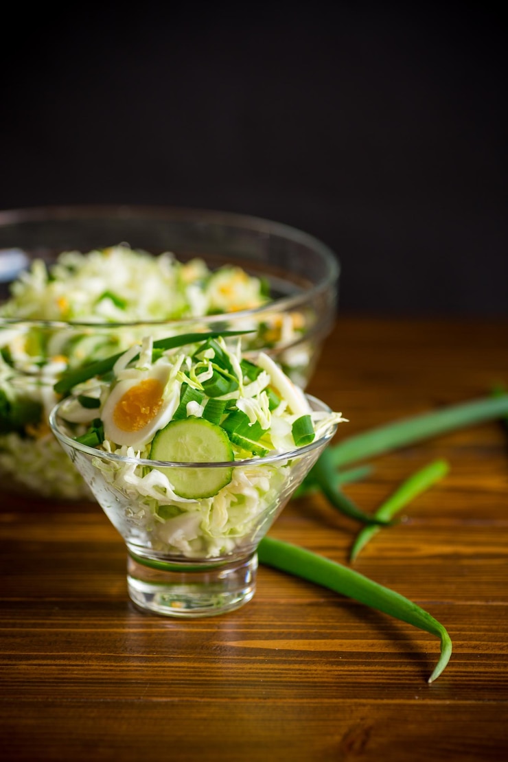 Foto salada primavera com repolho cedo pepinos ovos e cebolinha em uma mesa de madeira