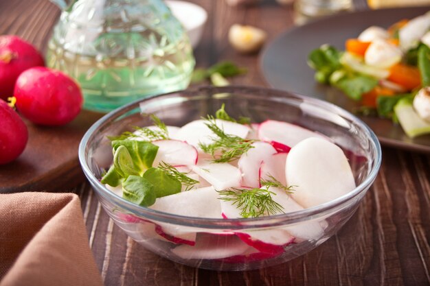 Salada primavera fresca com rabanete e manjericão na mesa de jantar