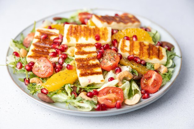 Foto salada quente com halloumi frito queijo nozes caju e amêndoas cereja tomates laranja e rúcula