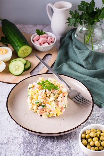 Salada russa Olivier tradicional de legumes cozidos e salsichas em um prato Visão vertical