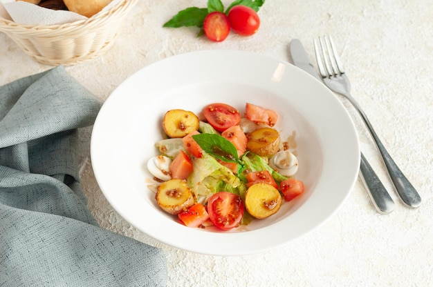 Salada rústica com batata assada, legumes e ovo de codorna. Temperado com molho de mostarda. Num prato branco. Perto está um garfo com uma faca e um guardanapo.