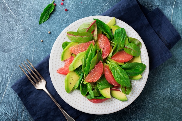 Salada saborosa útil de espinafre, acelga, abacate e toranja com azeite de oliva em uma superfície escura de concreto velho