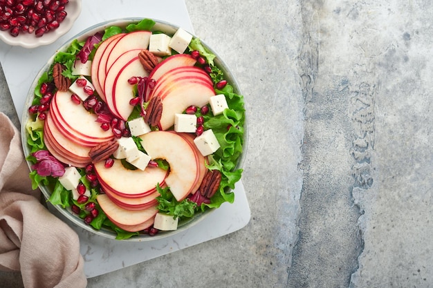 Salada Salada de frutas frescas verdes com queijo feta maçã romã noz-pecã e alface no prato branco Ideia para um inverno saudável e delicioso Salada de Natal Alimentação saudável e equilibrada Vista superior