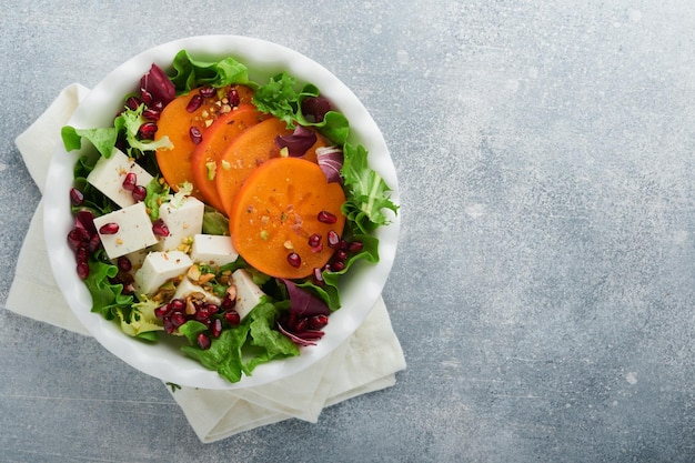 Salada Salada verde fresca com queijo feta, caqui, romã e pistache, no prato branco Ideia para um inverno saudável e delicioso Salada de Natal Alimentação saudável e equilibrada Vista superior