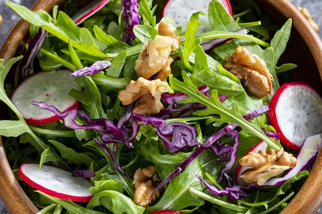 Salada saudável de baixas calorias com rúcula, rabanete, repolho roxo e nozes, close-up