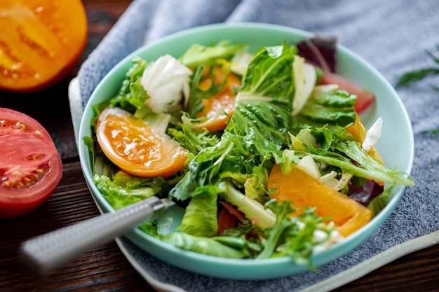 Salada saudável de legumes frescos, ervas e tomates em um fundo de madeira.