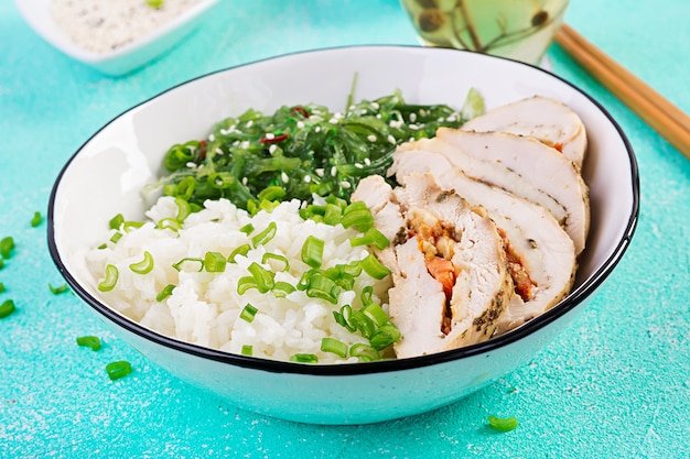 Salada saudável em uma tigela branca, pauzinhos. Rolinhos de frango, arroz, chuka e cebola verde.