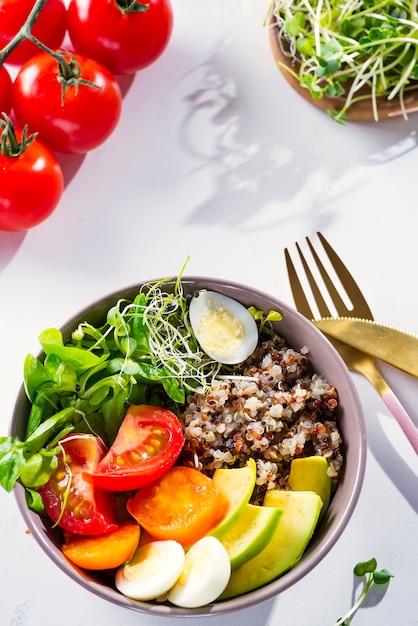 Salada saudável fresca com quinoa, tomate cereja e verduras mistas, abacate, ovo e micro verduras em mármore