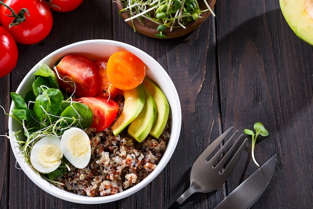 Salada saudável fresca com quinoa, tomate cereja e verduras mistas, abacate, ovo e micro verduras na madeira