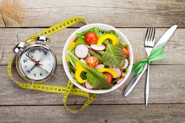 Salada saudável fresca e fita métrica na mesa de madeira