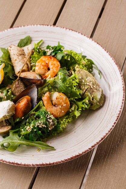 Foto salada saudável. receita de frutos do mar frescos. camarão grelhado, mexilhão e lula, salada de alface e purê de abacate.