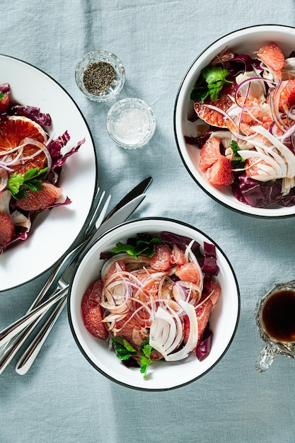 Salada siciliana com erva-doce, laranja, toranja e salada de radicchio com molho balsâmico sobre toalha de mesa de linho azul.