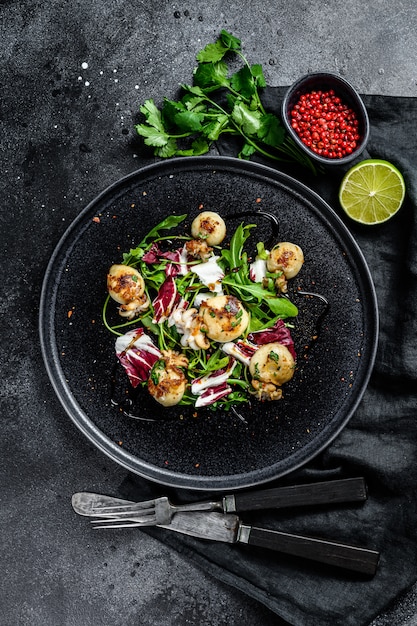 Salada tailandesa com lulas e rúcula grelhadas. Superfície preta. Vista do topo