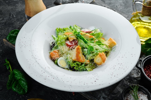 Salada tradicional de César com frango sobre um fundo de pedra preta