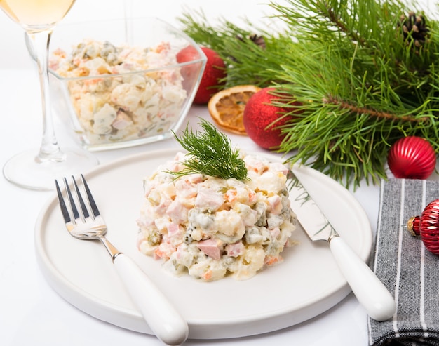 Salada tradicional de olivier de ano novo com decoração festiva em fundo branco, close-up