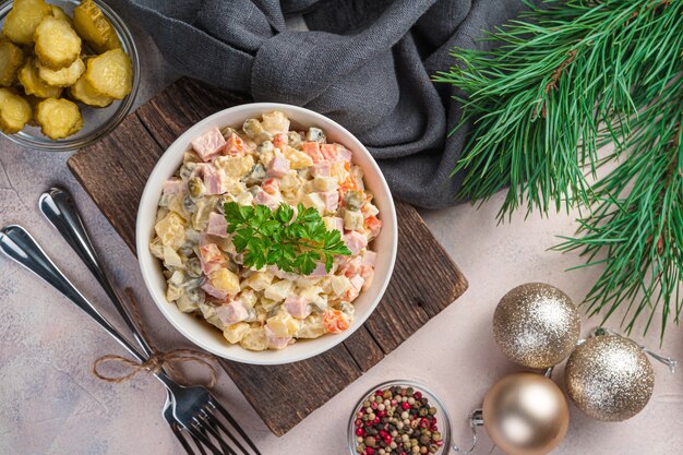 Salada tradicional de olivier de legumes picados e salsicha no fundo das decorações de Natal. Vista superior, horizontal.