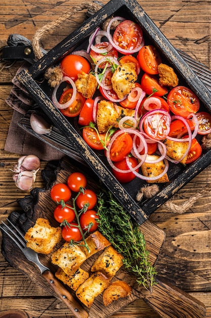 Salada tradicional italiana panzanella com tomate cebola e pão croutons em bandeja de madeira fundo de madeira vista superior