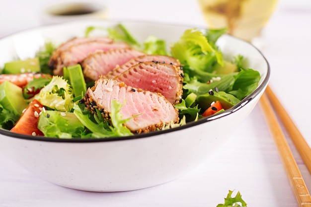 Salada tradicional japonesa com pedaços de atum Ahi grelhado médio-raro e gergelim com legumes frescos em uma tigela.