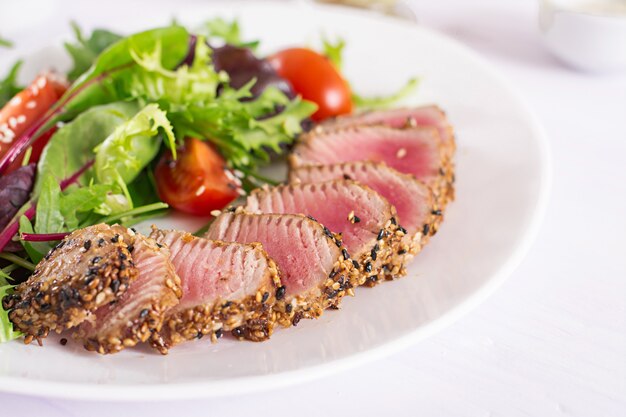 Salada tradicional japonesa com pedaços de atum ahi grelhado médio-raro e gergelim com salada de legumes fresca em um prato