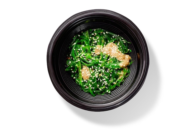 Salada tradicional japonesa hiyashi wakame com molho de amendoim e gergelim em tigela preta