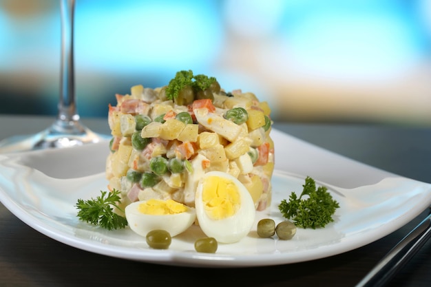 Salada tradicional russa Olivier, guardanapo de cor, mesa de madeira, fundo brilhante