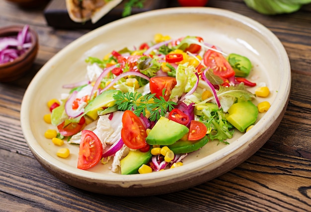 Salada vegan apetitosa de tomate, abacate, milho, cebola roxa e folhas de alface. Comida vegetariana saborosa. Comida vegetariana saudável. Salada vegetariana.