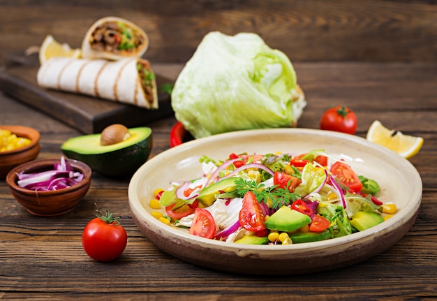 Salada vegan apetitosa de tomate, abacate, milho, cebola roxa e folhas de alface. Comida vegetariana saborosa. Comida vegetariana saudável. Salada vegetariana.