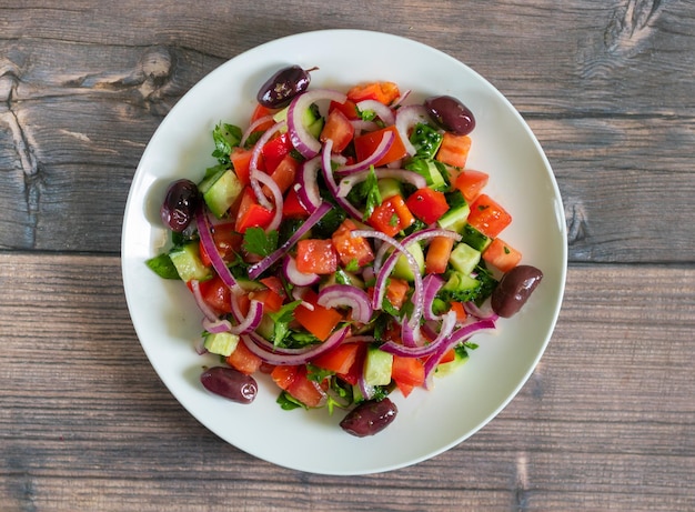 Salada vegana de tomates pepinos pimentões cebola roxa e azeitonas kalamata com azeite Vista superior centrada