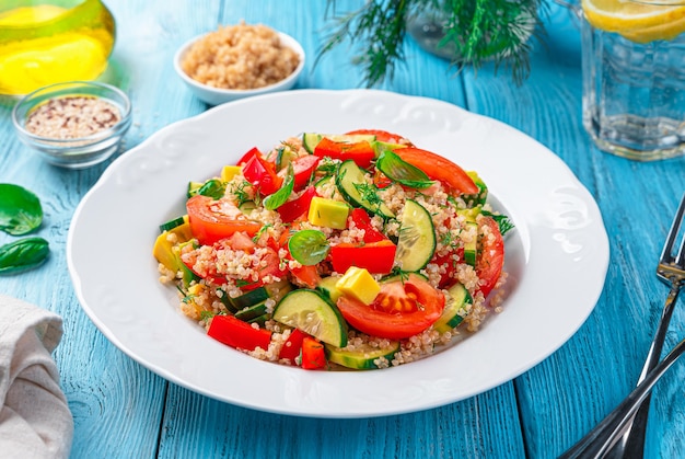 Salada vegetariana com abacate e quinoa e ervas frescas em um fundo azul Comida saudável Vista lateral horizontal