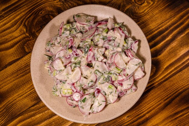 Salada vegetariana com cebola verde rabanete e creme azedo em um prato de cerâmica Vista superior