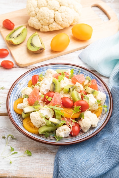 Salada vegetariana de couve-flor, kiwi, tomate, brotos de microgreen no branco