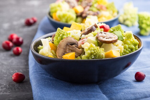 Salada vegetariana de repolho romanesco, champignon e abóbora em um fundo preto de concreto