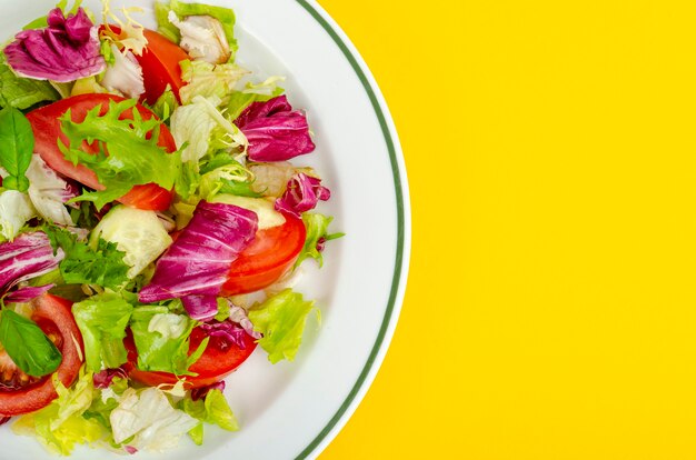 Salada vegetariana dietética leve no prato na mesa amarela