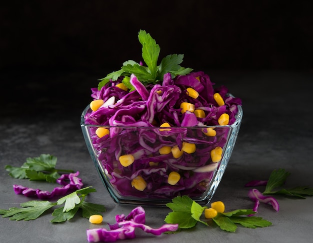 Salada vegetariana fresca com repolho roxo e milho em uma superfície cinza escura