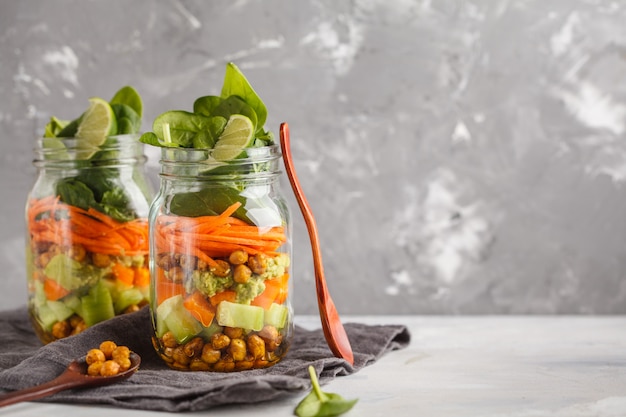 Salada verde caseiro em um frasco de vidro com grão de bico cozido, guacamole e legumes, copie o espaço. conceito de comida vegan de desintoxicação de dieta saudável.