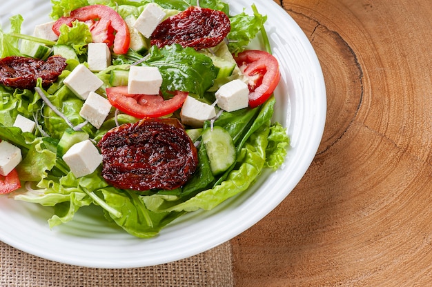 Salada verde com alface, rúcula, pepino, queijo e tomates secos.