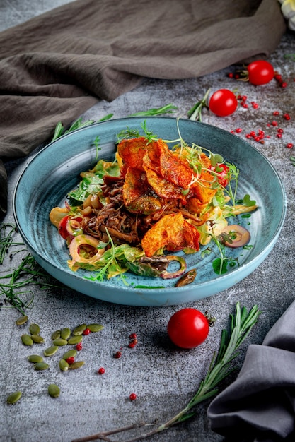 Salada verde com batatas fritas tomates cogumelos e carne com anéis de cebola roxa e rúcula