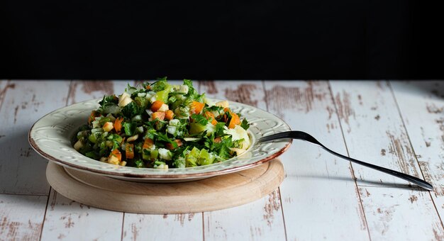 Salada verde com batatas pimentos cenouras endro salsa maçã cebola num prato vintage numa mesa de madeira