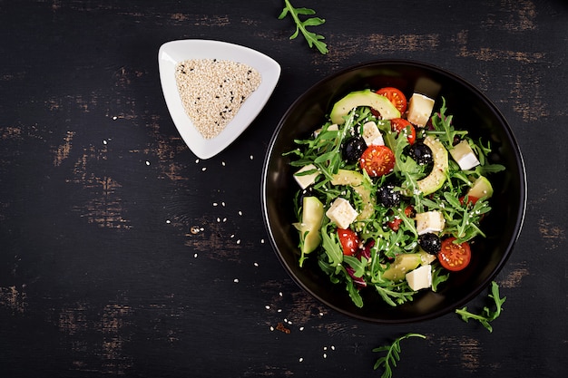 Salada verde com fatias de abacate, tomate cereja, azeitonas pretas e queijo