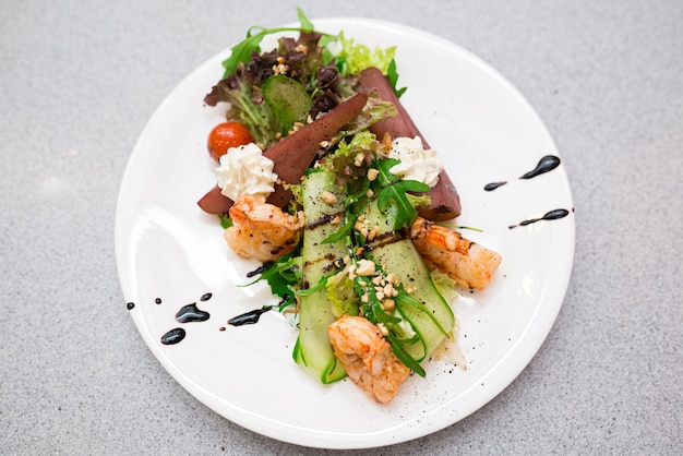 Salada verde com pêra bêbada pêra em vinho e camarão em molho de iogurte salpicado com nozes de pinheiro