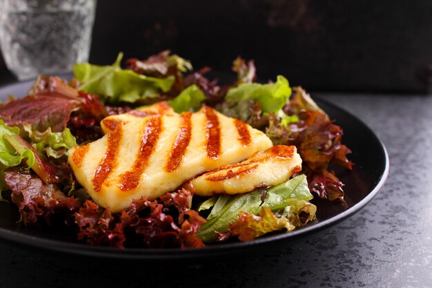 Salada verde com queijo halloumi frito em uma placa preta