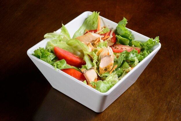 Salada verde com salmão em tigela branca na mesa de madeira