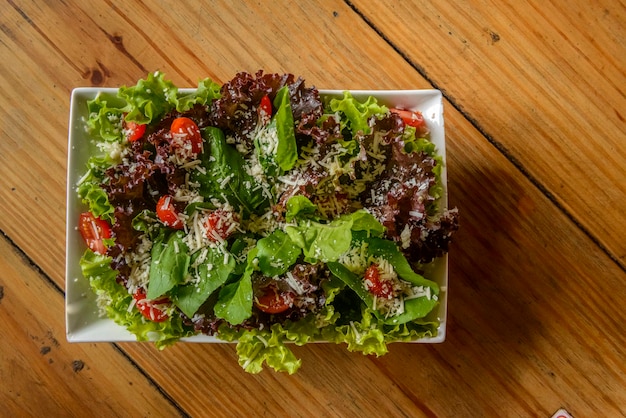 Salada verde em tigela branca na mesa de madeira