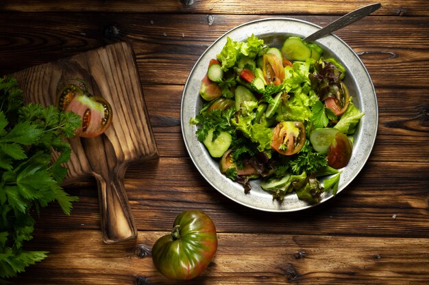 Salada verde fresca em uma tigela de metal na mesa de madeira. Estilo rústico.