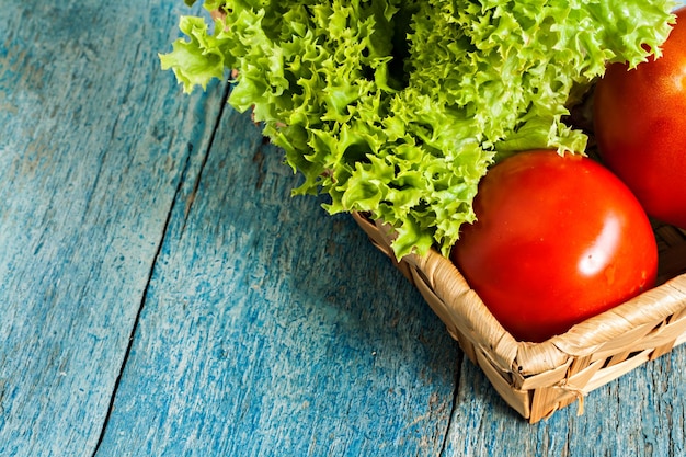 Salada verde fresca lola rossa e tomate sobre fundo azul de madeira