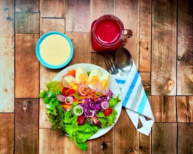 Salada verde mista com ovo cozido e suco de beterraba em fundo de madeira